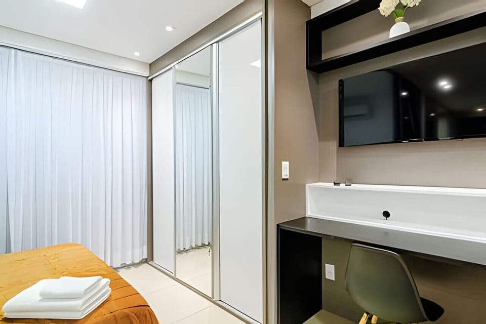 Sala/Quarto - Quarto com cama de casal, armário, espelho fullbody, balcão de leitura/reuniões, raque e televisão.