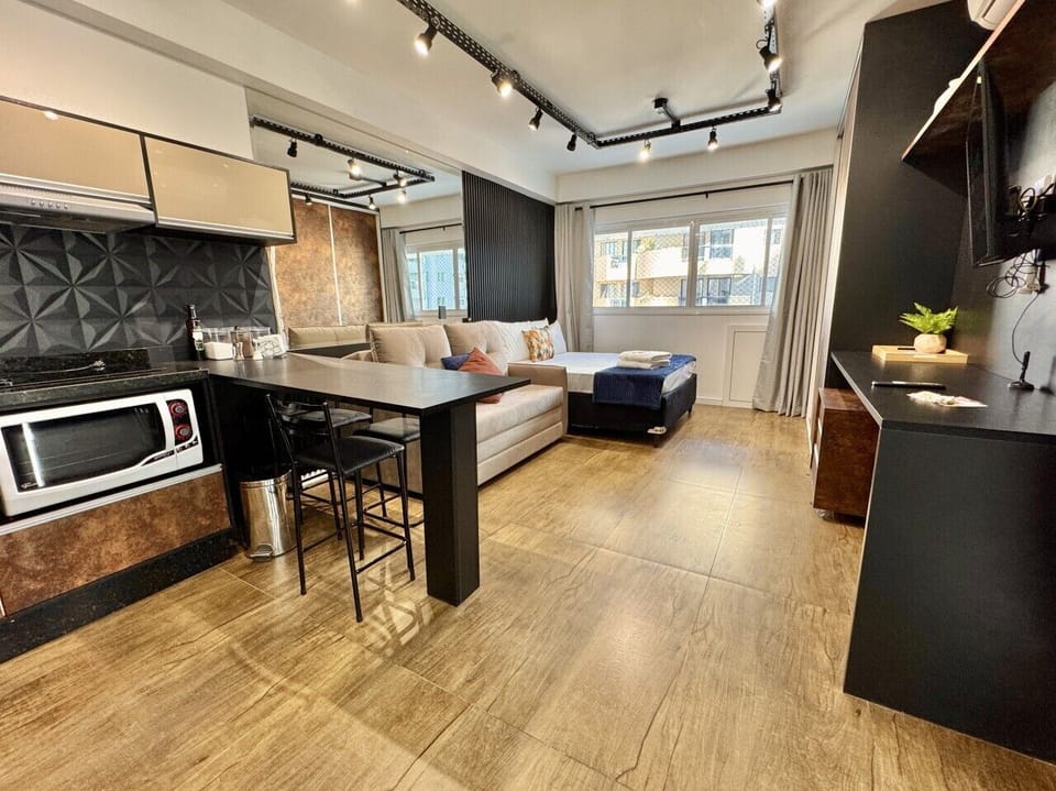 Studio amplo com design industrial: painel ripado preto e piso madeira