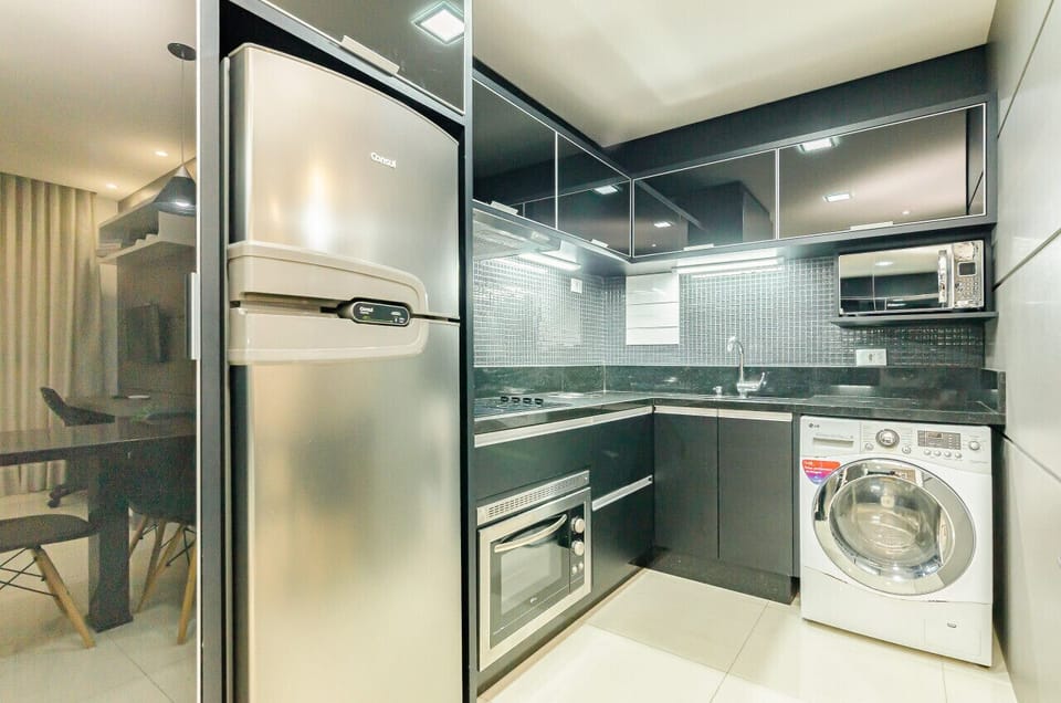 Cozinha moderna e completa com geladeira, forno, cooktop 4 bocas, exaustor, pia, armários, micro-ondas e lava e seca.