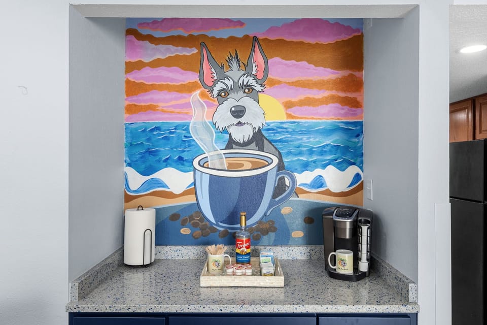 Start every morning at the coffee bar — Keurig or drip, coffee included. The schnauzer mural approves.
