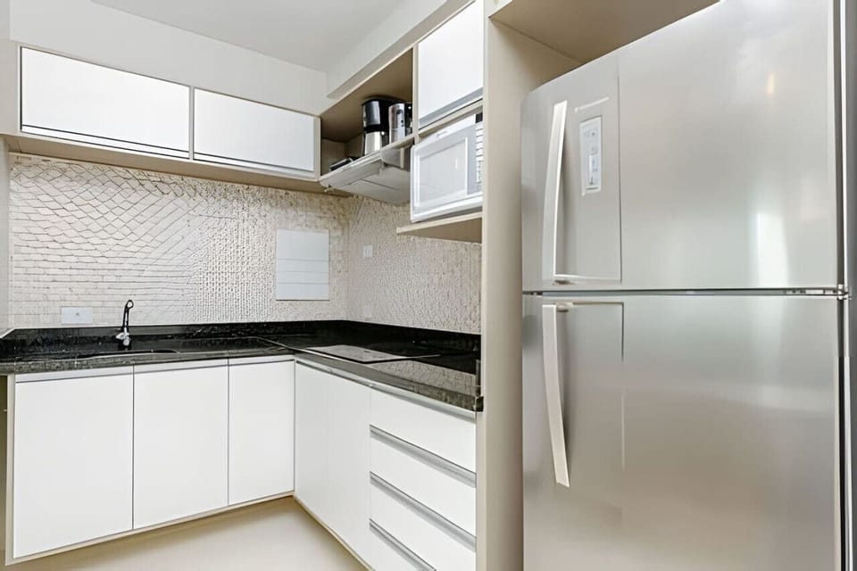 Cozinha equipada com geladeira, cooktop com 4 bocas de indução, pia, armários, cafeteira e grill.