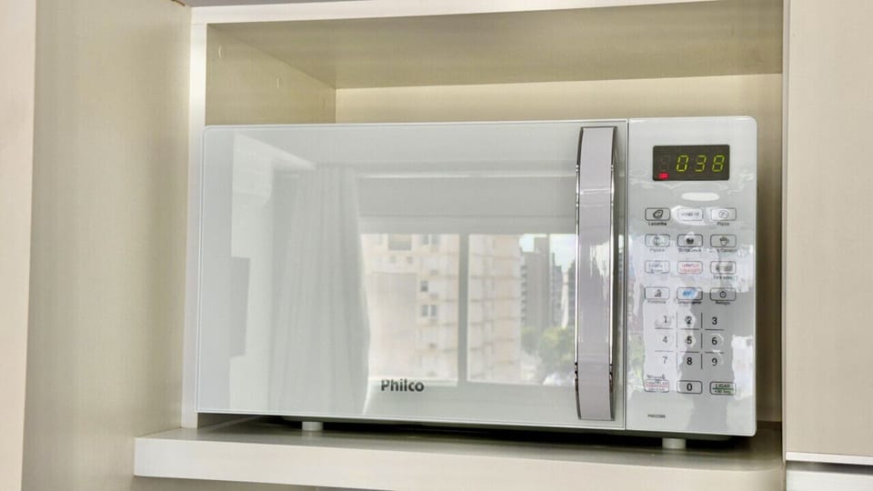 Microondas Philco branco com painel digital em cozinha compacta.