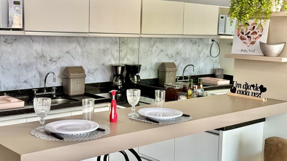 Cozinha integrada com bancada bege, marmore e eletrodomesticos