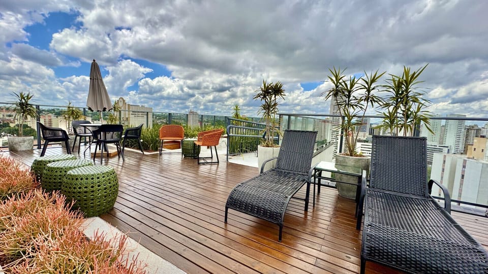 Rooftop com espreguicadeiras, deck de madeira e vista da cidade