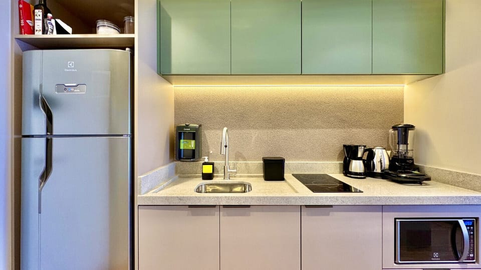 Cozinha equipada — geladeira, cafeteira Nespresso, cooktop e armarios verdes