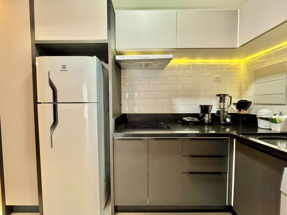 Cozinha moderna com bancada preta, cooktop e armarios brancos