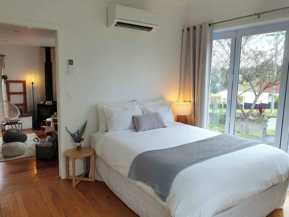 Queen size bed with private entrance to room and direct access to shared kitchen and lounge spaces. Garden and sunset views.