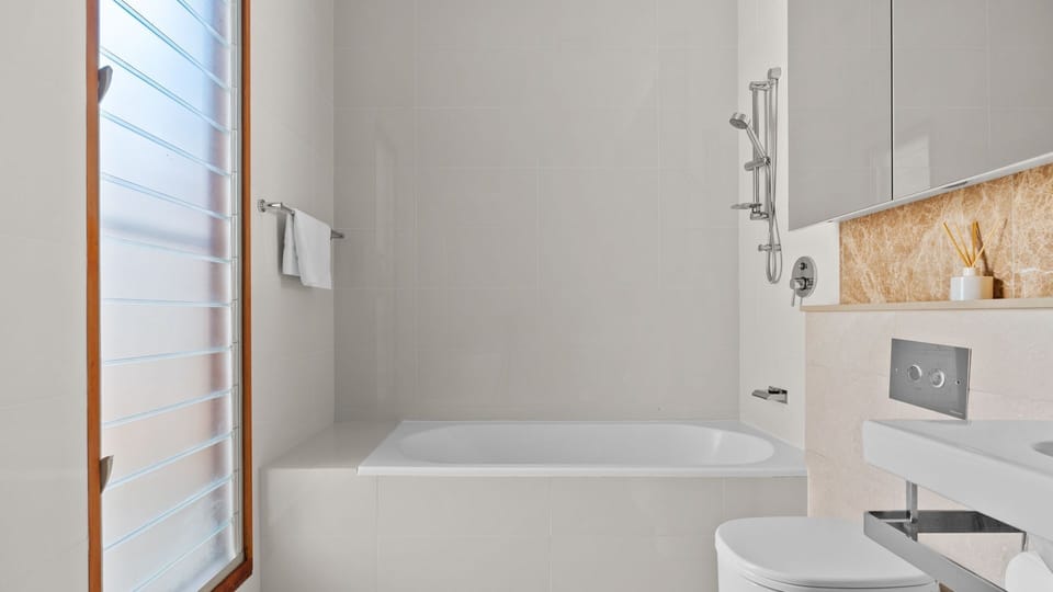 Clean and modern bathroom with a bath and shower combo.