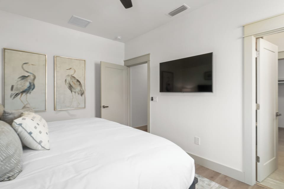 Drift into peaceful sleep in your bright, airy bedroom with plush bedding and wall-mounted TV for cozy evening relaxation.