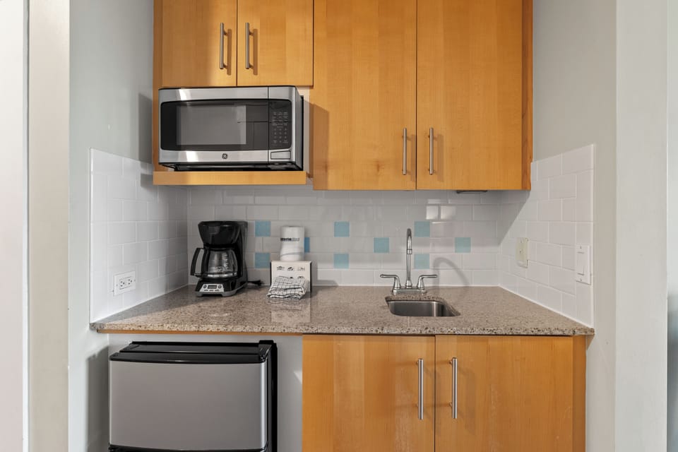 Compact kitchenette with a mini-fridge, microwave, and coffee maker.