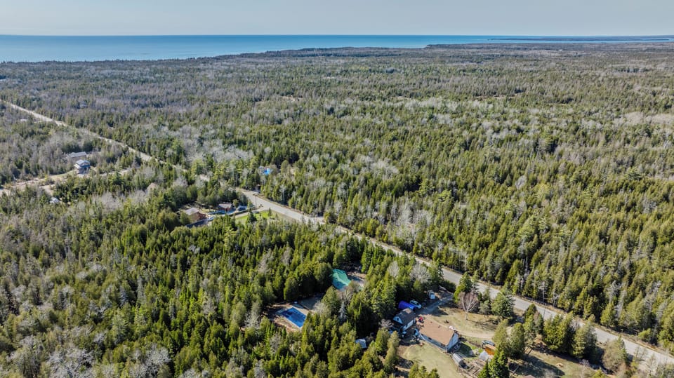 Scenic aerial view of a wooded coastal region with private properties—ideal for serene vacation rentals and nature-filled getaways.