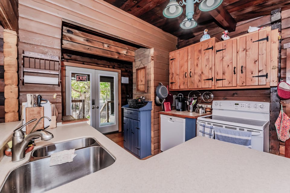Whip up home-cooked meals in this fully equipped kitchen at a cozy log cabin vacation rental—featuring rustic cabinetry, modern appliances, and direct access to the outdoors. A perfect base for scenic getaways and family-friendly adventures.