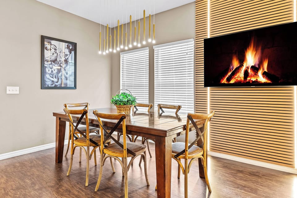 Enjoy meals at our stylish wooden dining table, surrounded by charming crossback chairs perfect for conversations. The warm glow of unique pendant lighting and a modern fireplace creates a cozy ambiance for every occasion.