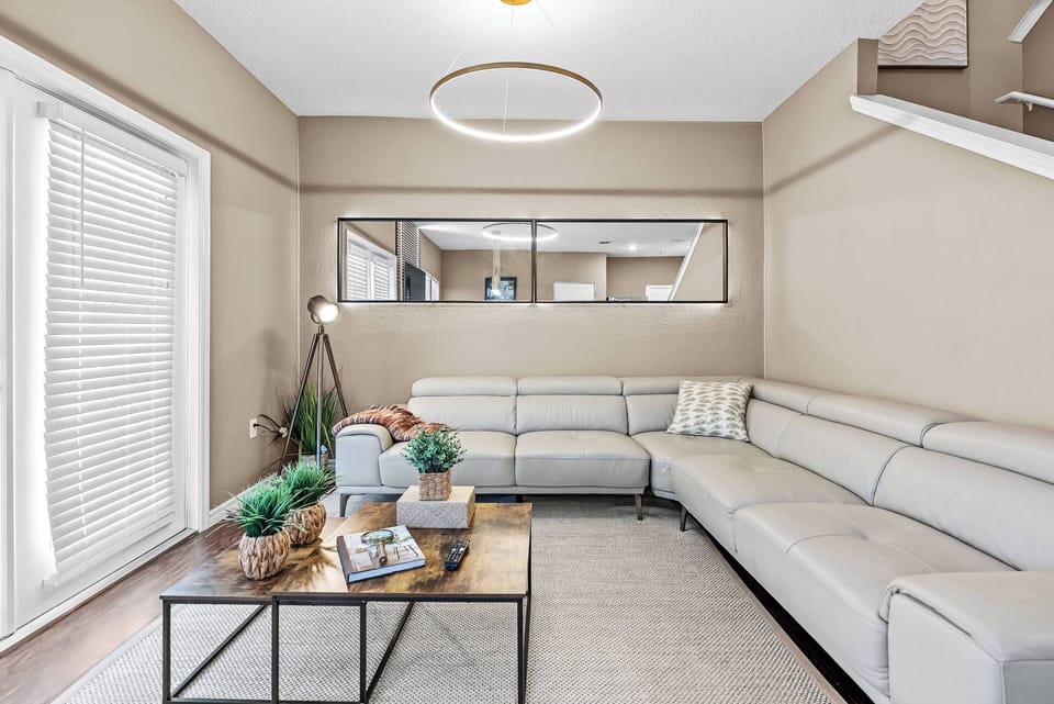 Natural light pours in through the large windows, enhancing the warm tones of this cozy living room. The sleek leather sectional invites you to unwind, while the stylish coffee table adds a touch of sophistication to your stay.