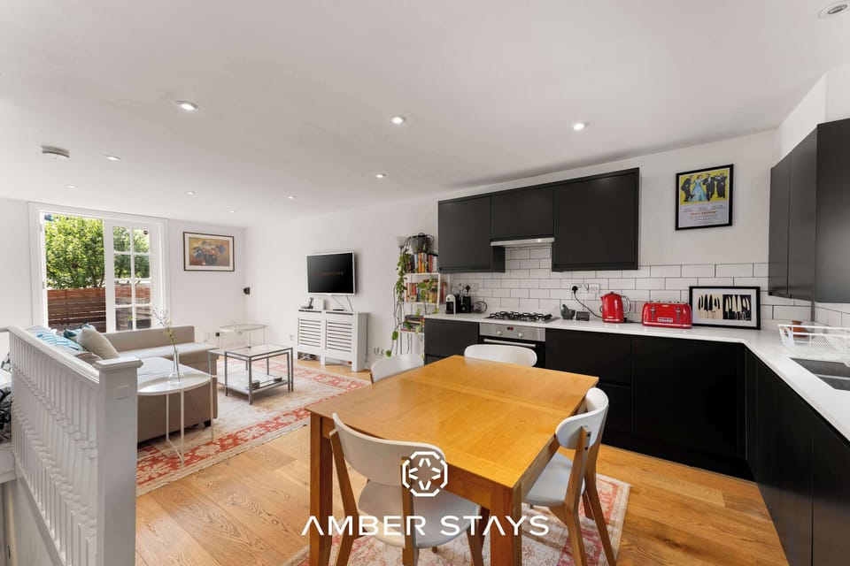 The warm wooden dining area and four sleek white chairs create a central spot for meals and socializing. It sits right on a beautiful patterned rug, which helps define the dining space within the larger room while keeping.