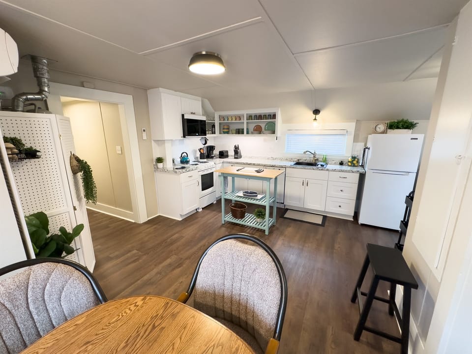 Kitchen, with dining table in the foreground. The well-appointed kitchen has a range/oven, microwave, fridge, dishwasher, and countertop toaster and coffee maker. 
