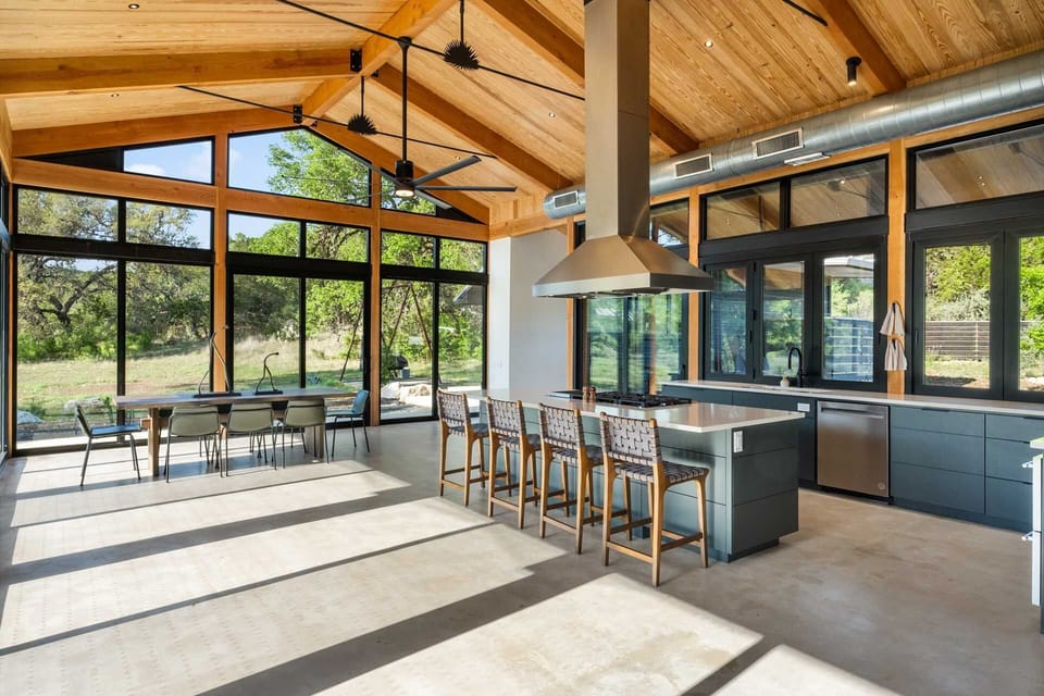 Chef's kitchen with bar seating and floor-to-ceiling windows-cook with a view and dine in nature's light.