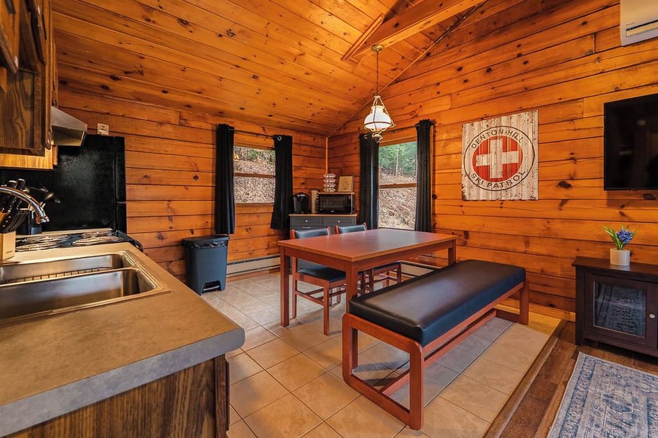 Warm cabin dining area with wood finishes, plenty of seating, and rustic charm — perfect for meals, games, or planning your next adventure.