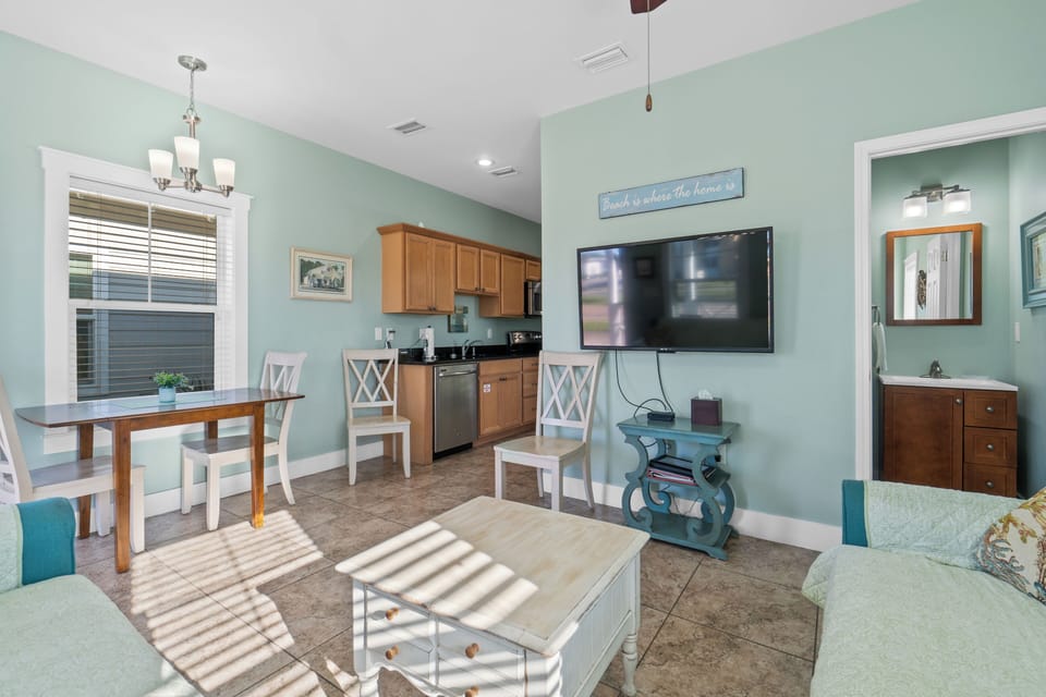 Relax in your bright, airy living space where soft mint walls create a coastal vibe and natural light streams in.