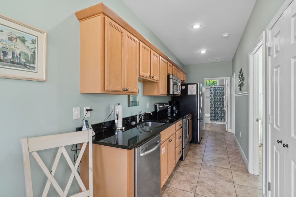 Your fully-equipped galley kitchen features granite countertops, stainless appliances, and warm wood cabinetry - perfect for preparing meals during your stay.