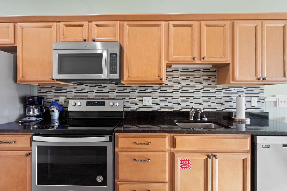 Cook your favorite meals in this fully-equipped kitchen with granite counters, stainless appliances, and modern backsplash.