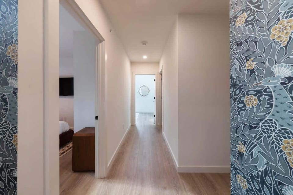 Vibrant and inviting hallway with a bold blue bird accent wall, creating a vibrant and welcoming transition to the living spaces.