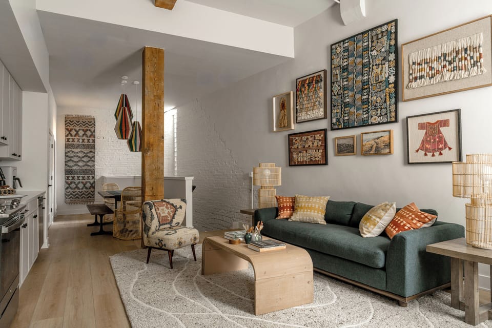 Open-concept with colorful textiles, a green sofa and curated art on the walls.