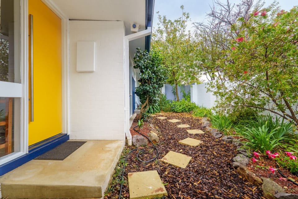 Welcoming facade with a sunny yellow front door and a peaceful garden that offers total privacy.