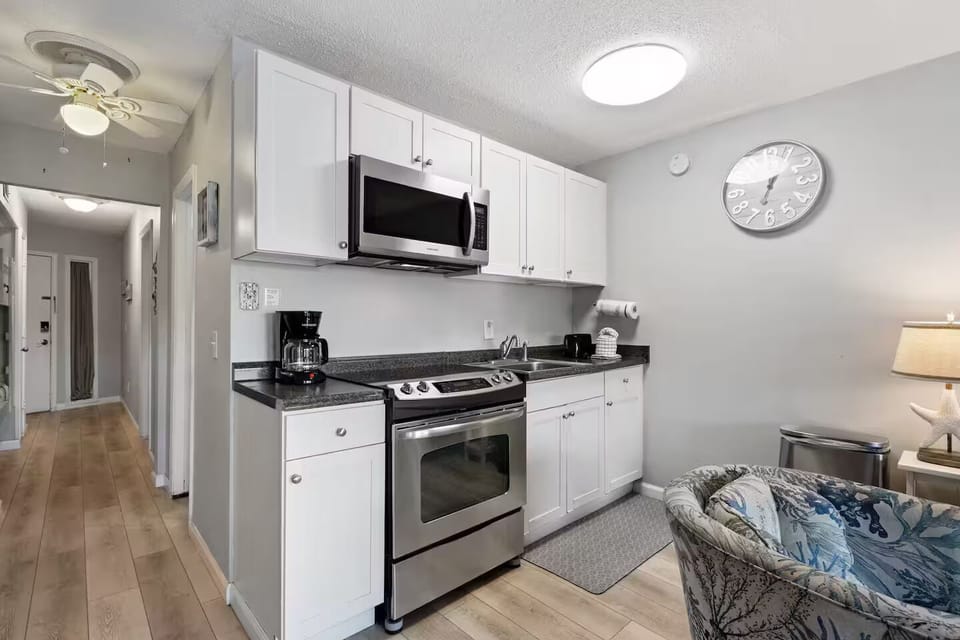 Kitchen with full size refrigerator, oven, microwave, sink, pots and pans