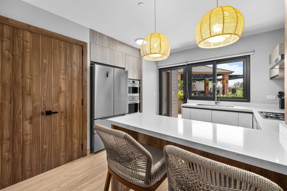 Check out this cozy kitchen setup! Those pendant lights and comfy stools make it a great spot for casual meals or morning coffee while enjoying the view.