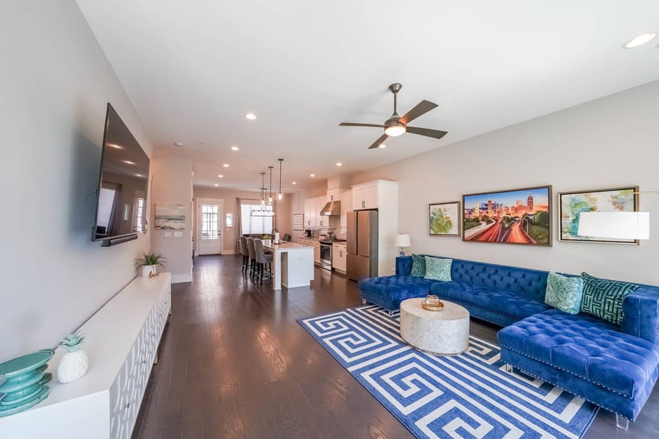 Living Room & Kitchen Open-concept living with plush sectional, gourmet kitchen, and smart TV. #AtlantaRental #ModernDesign #LuxuryStay