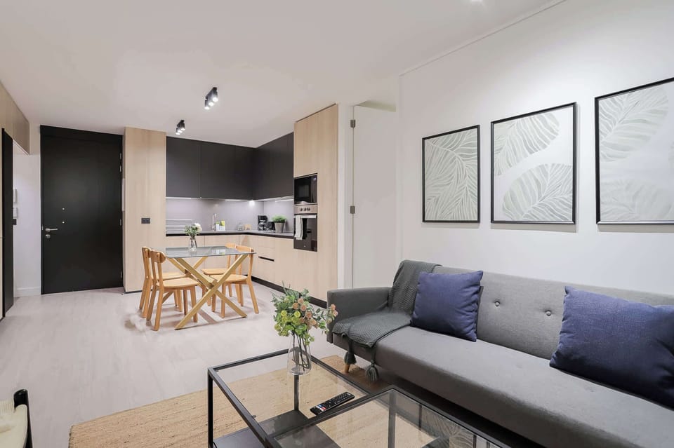 Stylish open-plan living area with a cozy sofa and modern kitchen, perfect for relaxing and entertaining.