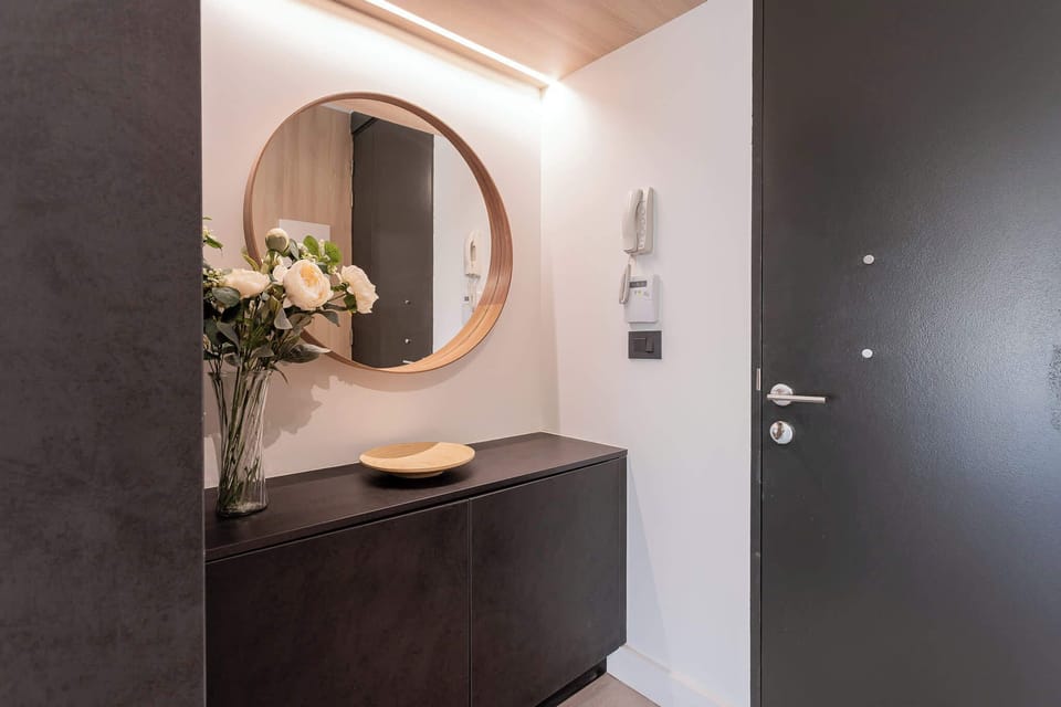 Step into a modern and inviting entryway, featuring elegant decor and a touch of nature with fresh flowers.
