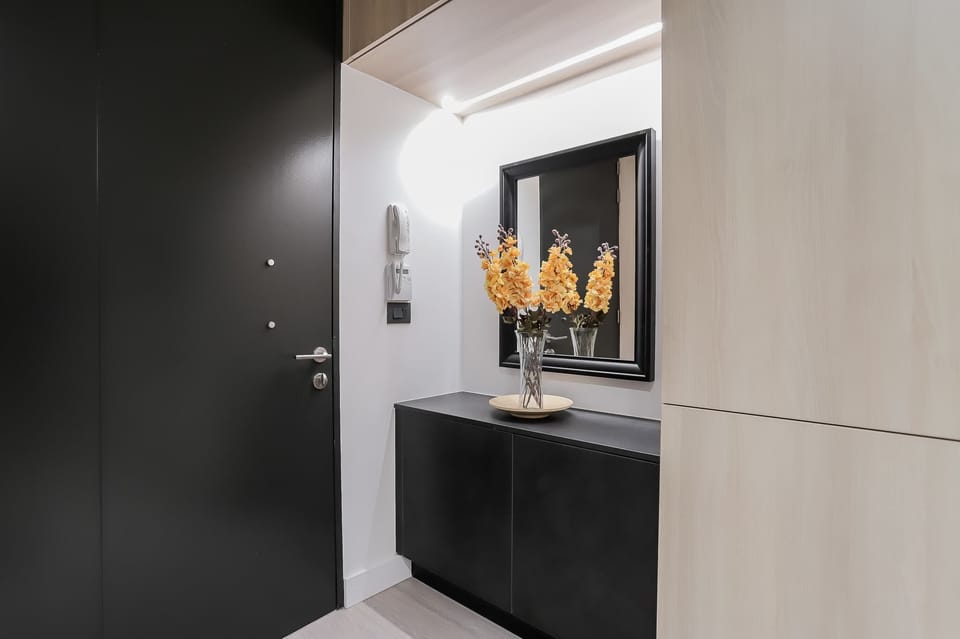 Welcome to a sleek and modern entryway with vibrant floral accents and stylish decor, setting the tone for a chic stay.