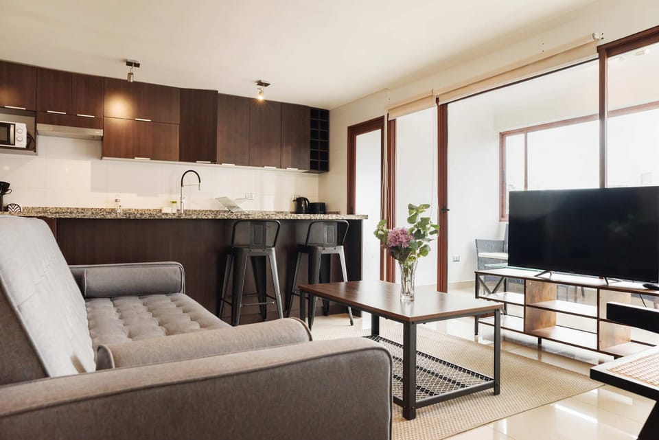 Modern living area with sleek kitchen, cozy seating, and balcony access for a relaxing stay.