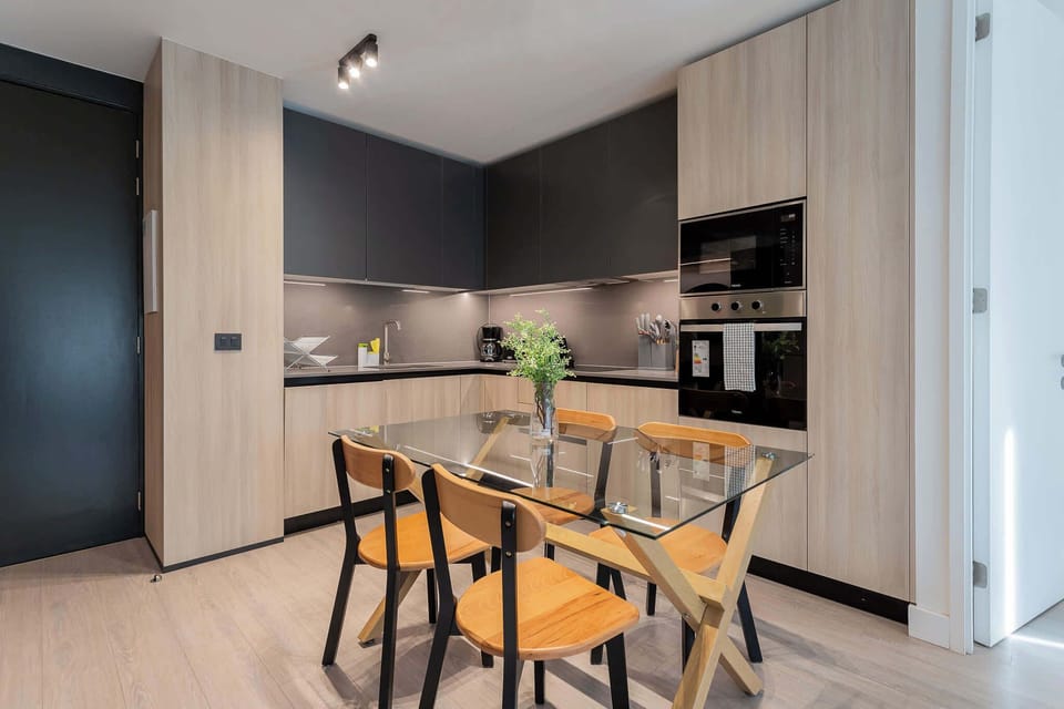 Experience modern living in this stylish kitchen, featuring sleek cabinetry and a cozy dining area perfect for meals and gatherings.