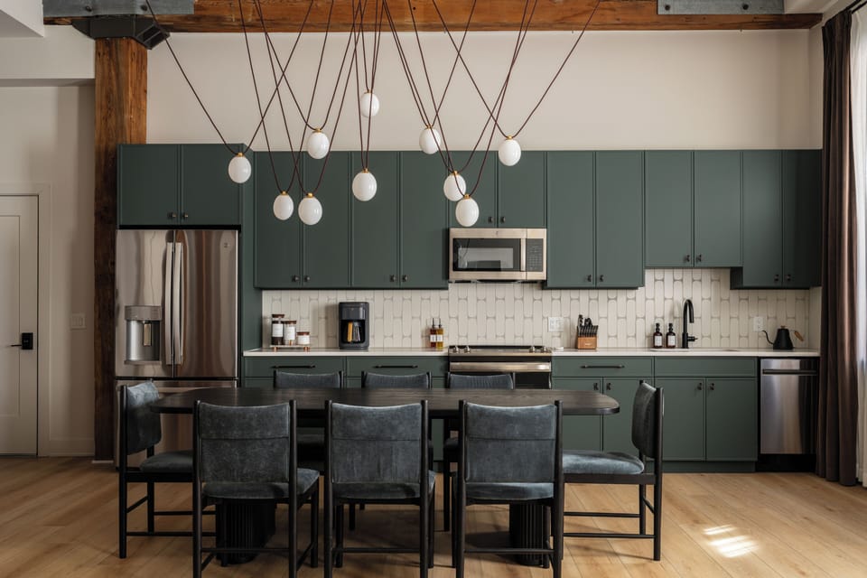 Stylish dining with dark wood table, velvet chairs, and bold chandelier above.