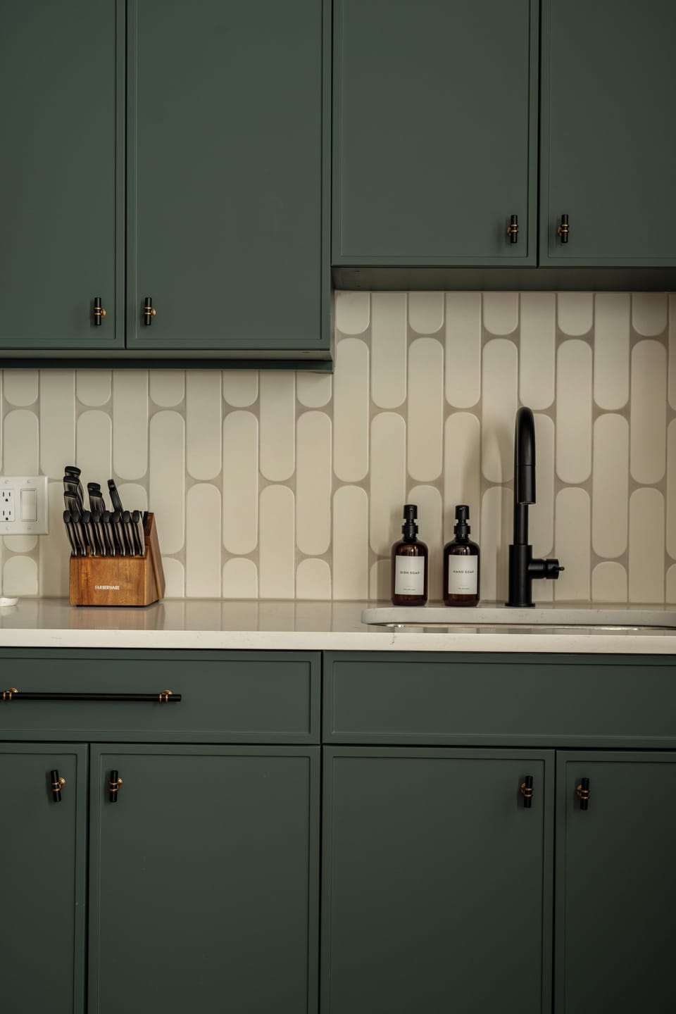 Green cabinets and unique tile add charm to this curated kitchen corner.
