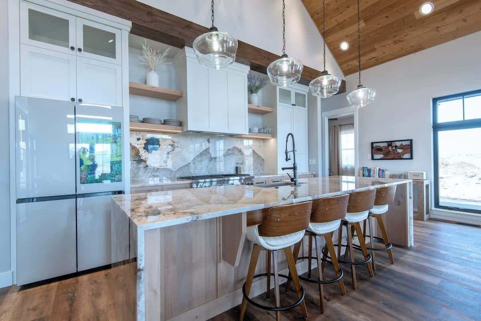 Kitchen island with bar seating, pendant lights, and direct Teton window views — the rare kitchen where cooking feels like the best part of the day.