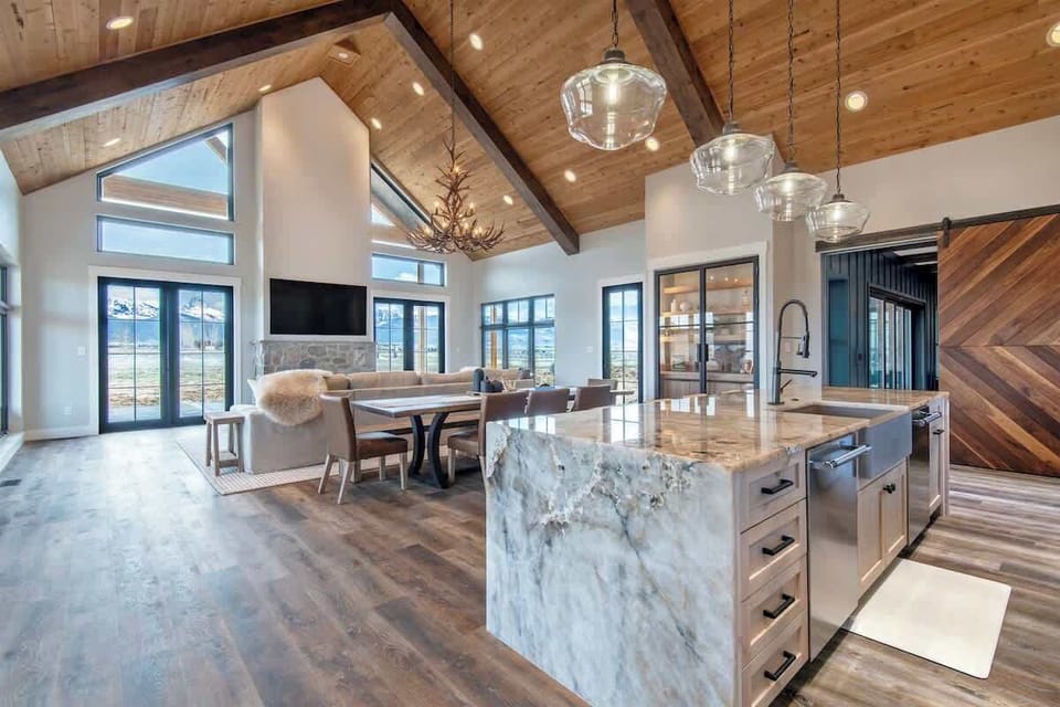 Dining room with plank vaulted ceiling, antler chandelier, and a kitchen island that anchors one of the most breathtaking open-plan spaces in the valley.