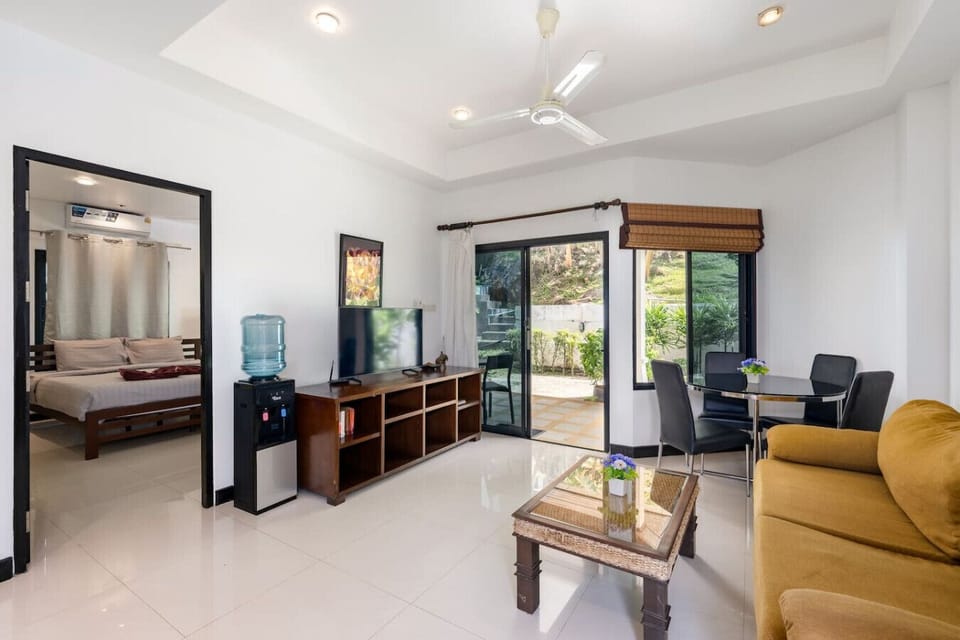 Open-plan living room with sofa bed for a second sleeping area, flat-screen TV, and modern decor in Koh Samui bungalow