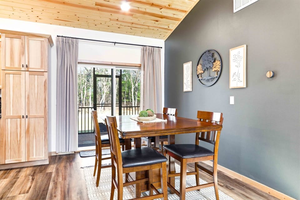 Your pub-height dining with a sliding glass door to the deck — step outside with your coffee or keep the door open and eat with a forest breeze.