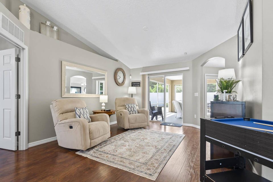 Step into the front sitting room featuring cozy recliners, a mini pool table, and inviting views of the back patio.