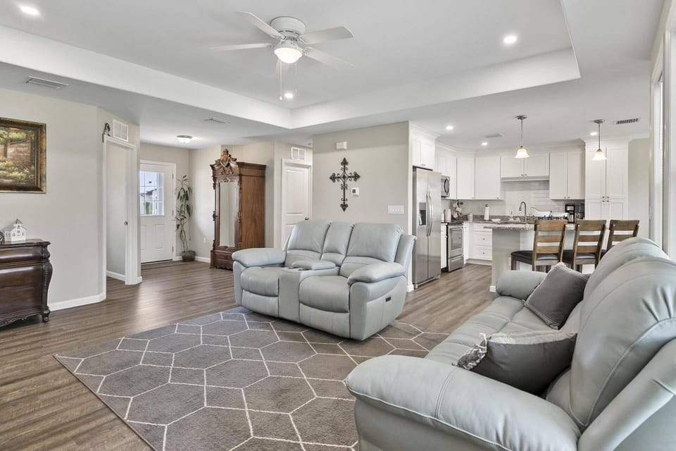 Open concept living area with comfortable seating and a large flat-screen TV, designed for relaxation and entertaining in a spacious, airy setting.