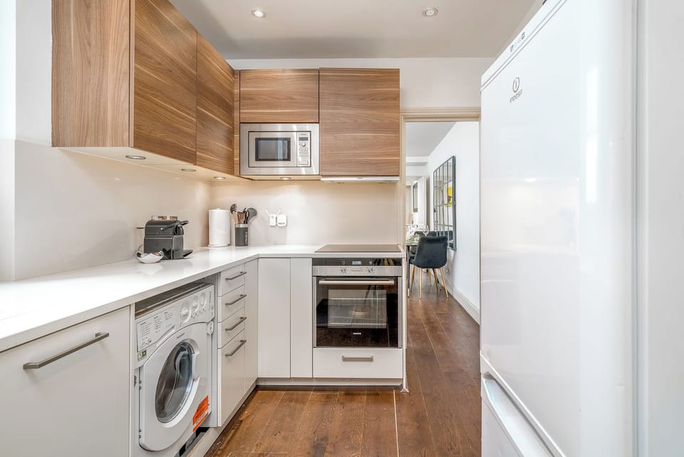 The kitchen features sleek white countertops ad maple overhead cabinets providing a clean and modern aesthetic. The induction cooker offers precise and efficient cooking, allowing you to prepare your favorite dishes with ease. 
