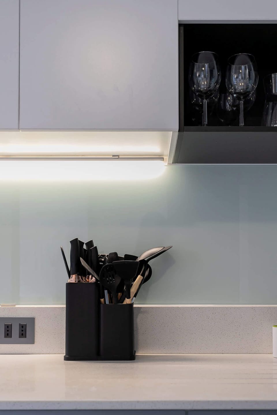 Sleek and modern kitchen with essential utensils and elegant glassware, perfect for culinary enthusiasts.