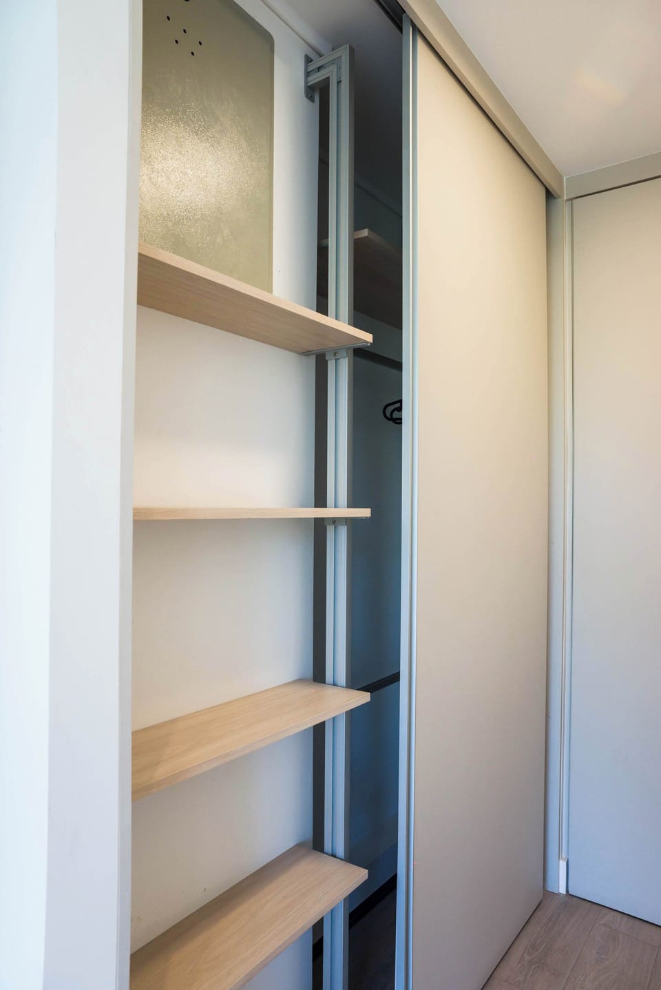 Organize your belongings with ease in this spacious closet featuring sleek shelving and modern sliding doors.