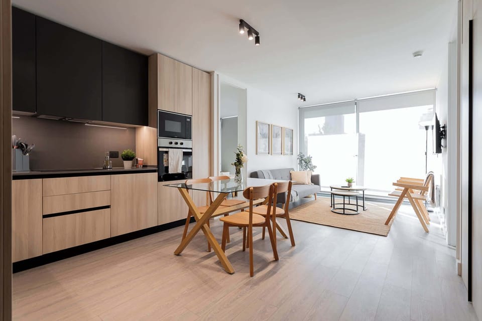 Modern and cozy open-plan living space with a sleek kitchen and abundant natural light, perfect for relaxation and dining.