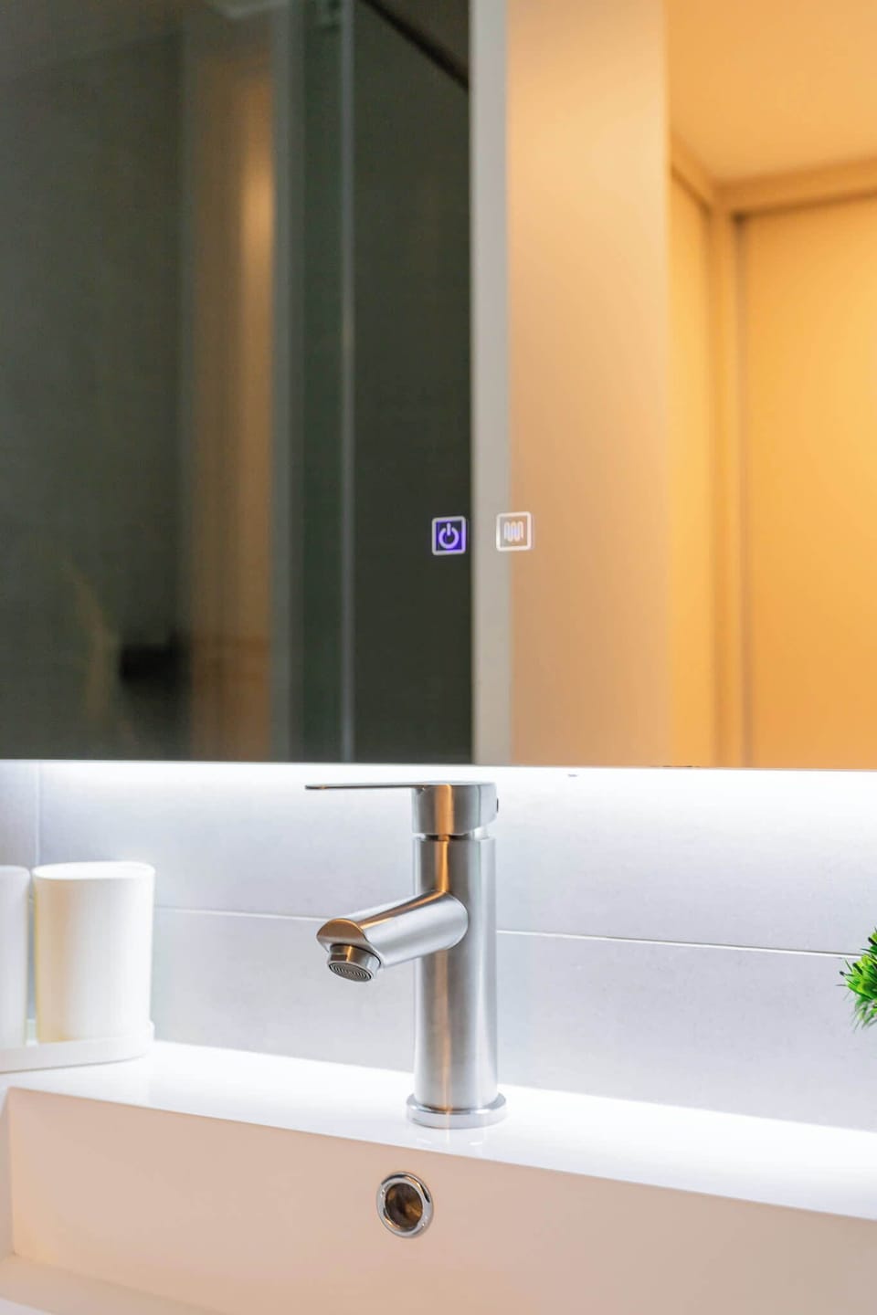 Experience modern elegance in this sleek bathroom featuring a stylish faucet and backlit mirror for a refreshing retreat.