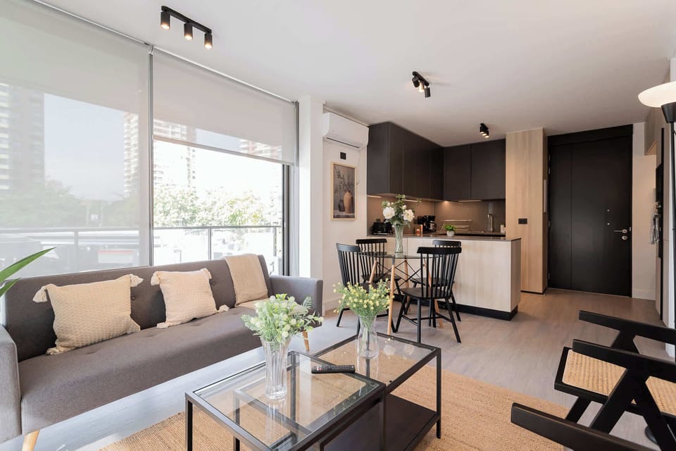 Chic and modern living space with a cozy sofa, stylish dining area, and sleek kitchen—perfect for a relaxing stay in the heart of Chile.